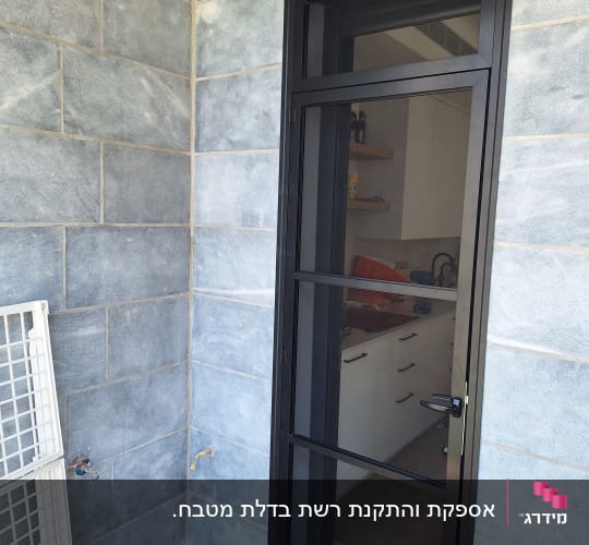 דלת אלומיניום שחורה על רקע קיר אפור